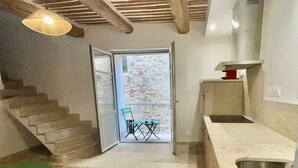 Eine moderne Küche mit integriertem Spülbecken, ein Essbereich mit Tisch und Stühlen sowie eine Treppe, die zu einem Außenbereich führt.