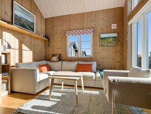A cozy living room with a wooden interior, a sofa set, a coffee table, and a window with a view.