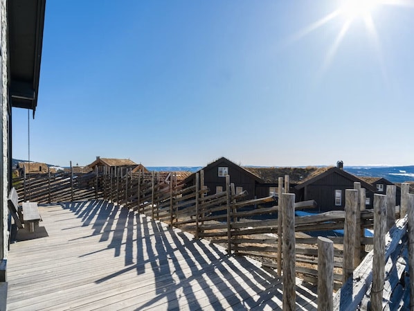 A wooden deck with thatched-roof cabins, a clear sky, and the ocean in the background.