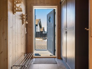 A wooden hallway leading to a door with a view of a building outside.