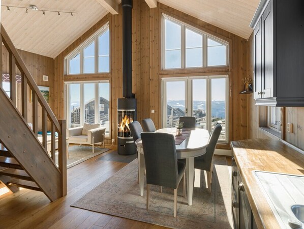 A spacious living area with a large window, a fireplace, and a dining table.