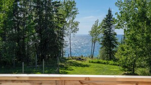 Eine Holzterrasse mit Blick auf eine Wiese und Bäume.