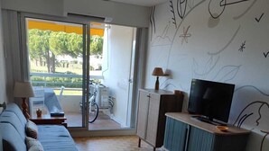Een moderne woonkamer met een bank, televisie en een balkon met een fiets.
