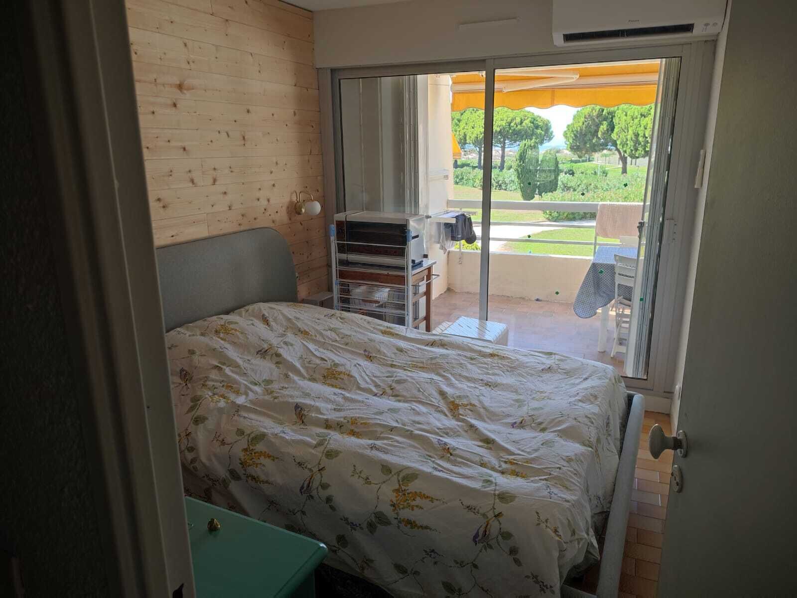 Makuuhuoneessa on sänky, pieni pöytä, vaatekaappi ja liukuovet, jotka johtavat ulkotilaan, jossa on pöytä ja tuoleja.