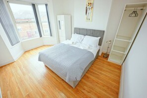 A bedroom with a bed, a wardrobe, a painting, and a window. - Upscale 3 BDR Modern Home in Anfield Liverpool (Liverpool)