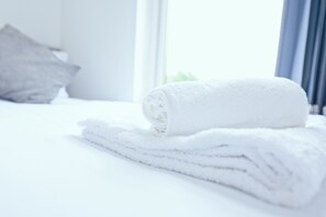 A neatly made bed with a rolled white towel and a folded white towel on top. - Upscale 3 BDR Modern Home in Anfield Liverpool (Liverpool)