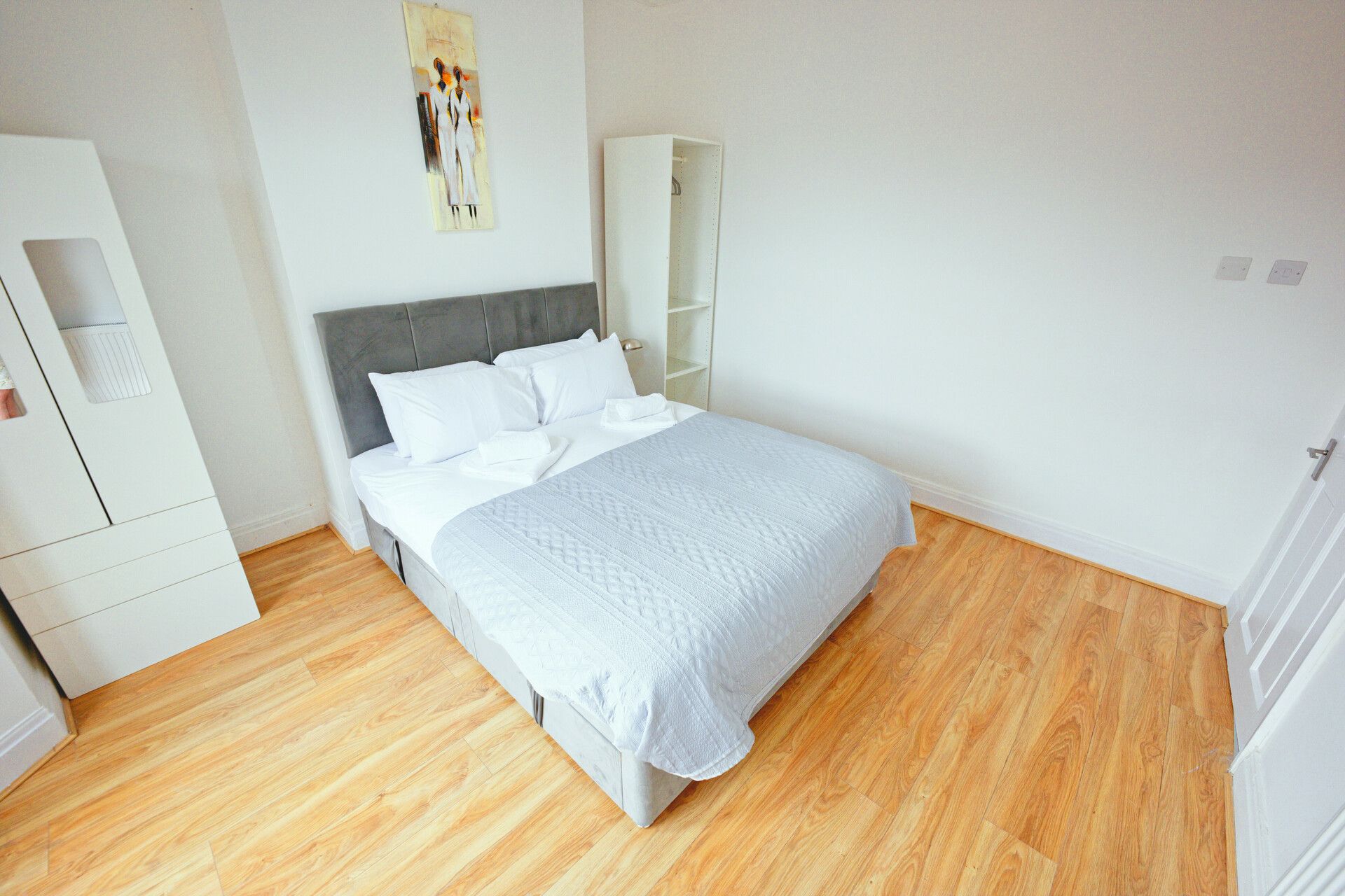 Ein Schlafzimmer mit einem Bett, einem Kleiderschrank und einem Wandbild.