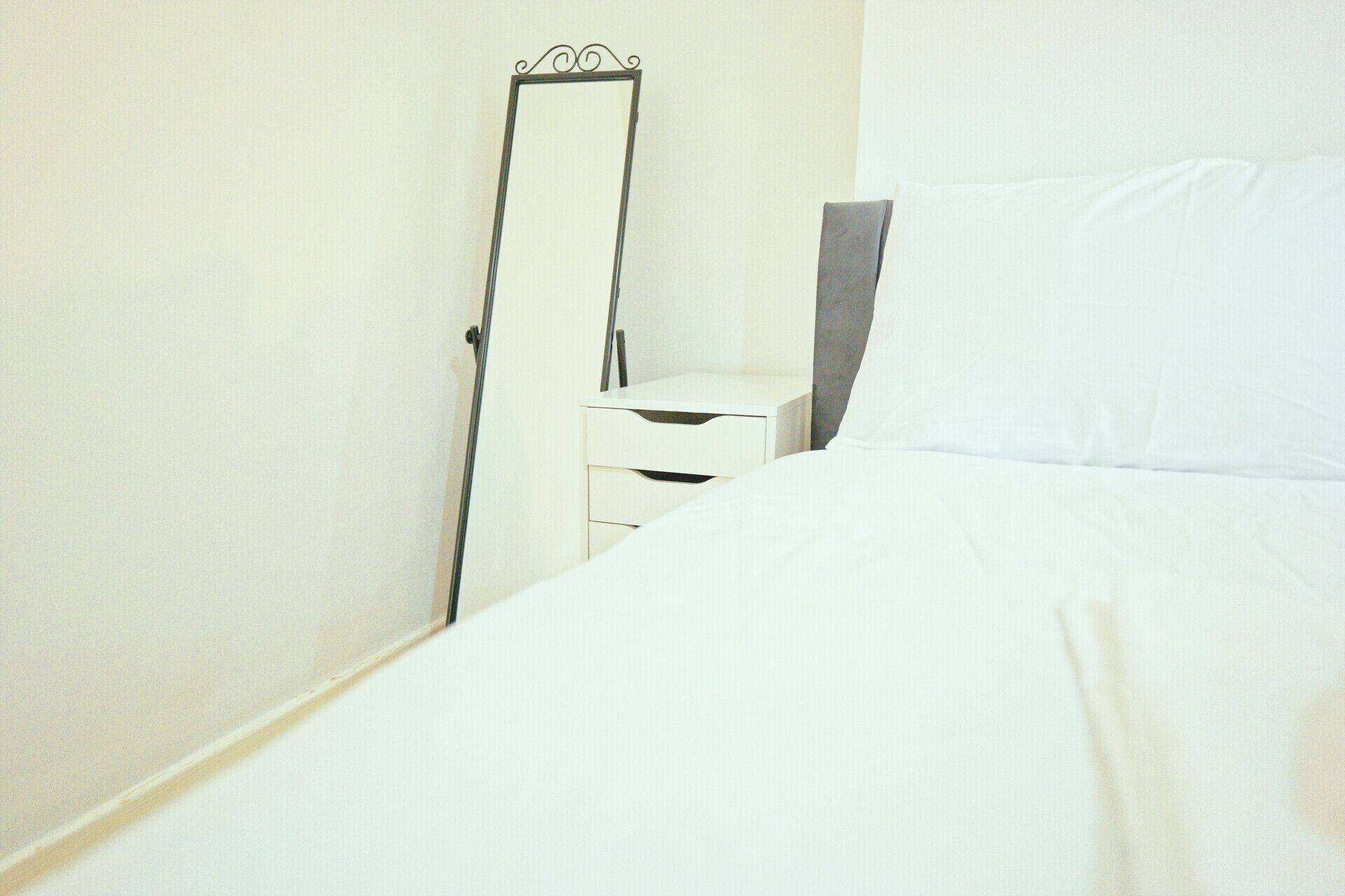 Un dormitorio con cama, mesita de noche, espejo y cómoda.