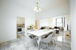 A modern kitchen with a built-in oven, a dining area with a white table and chairs, and a living room with a sofa and a TV. - Upscale 3 BDR Modern Home in Anfield Liverpool (Liverpool)
