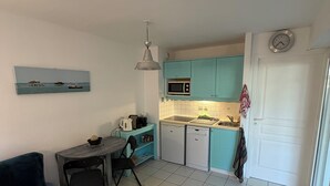 A compact living space with a kitchenette, a dining area, and a sofa. - Appartement T2 de 30 m2 Maubuisson, Proche lac et plage (Carcans)