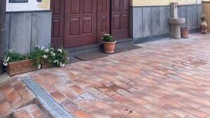 Ein Gebäude mit einer großen Holztür, einem kleinen Balkon mit Blumentöpfen und einer Steinfunktion.
