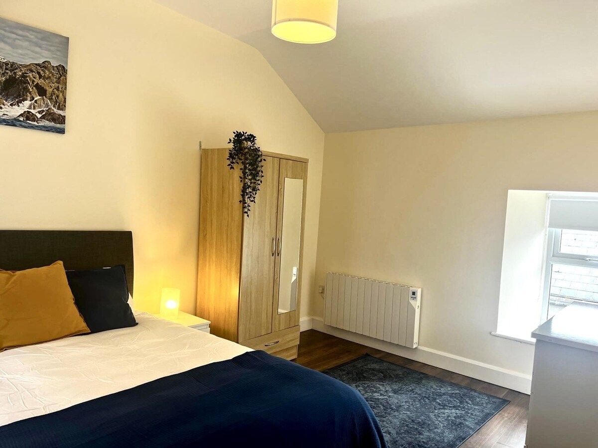 A bedroom with a bed, a wardrobe, a radiator, and a window.