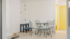 A dining area with a table and chairs, a pet bed, and a small table with a bowl.