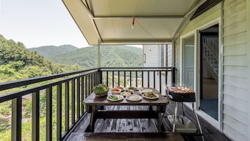 A wooden deck with a table set for a meal, overlooking a mountainous landscape.