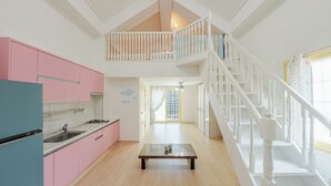 Cozinha espaçosa com armários cor-de-rosa, uma mesa de jantar de madeira e uma escada para um andar superior.