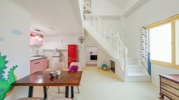 Una cocina con un refrigerador rojo, una escalera blanca y un comedor con una mesa de madera.