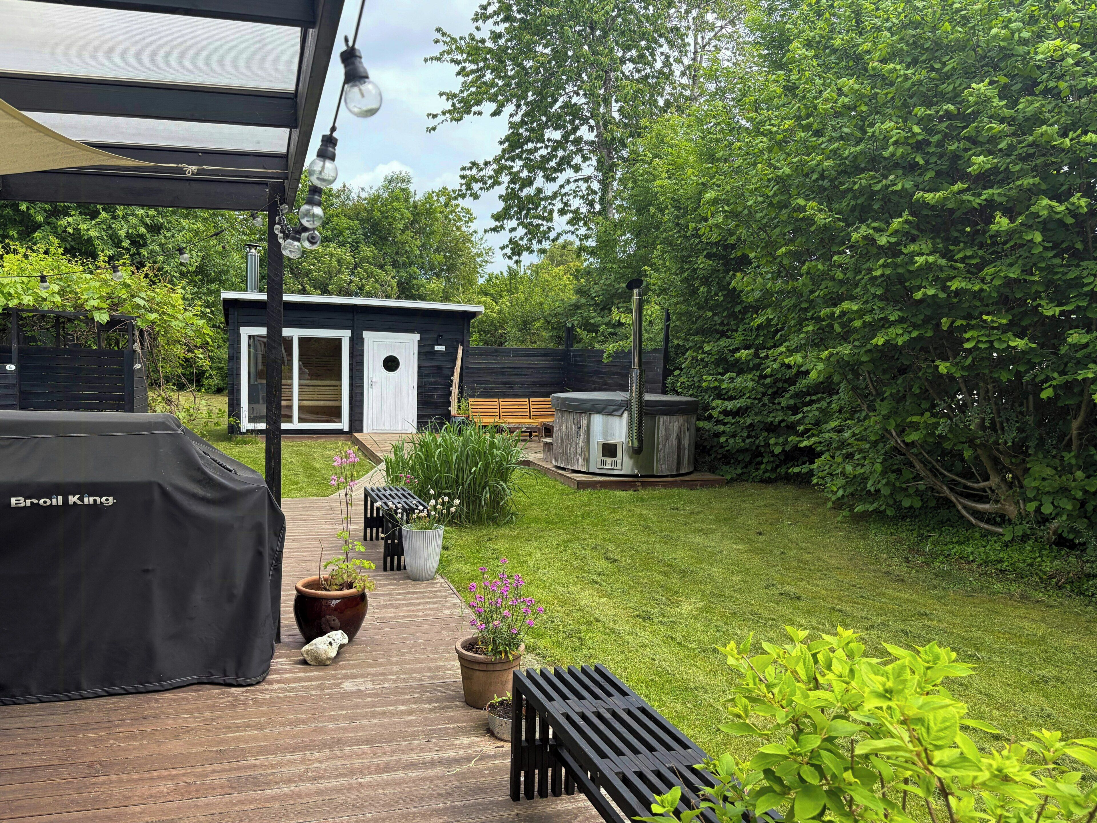 En trädgård med en grill, ett bubbelbad och ett trädäck.