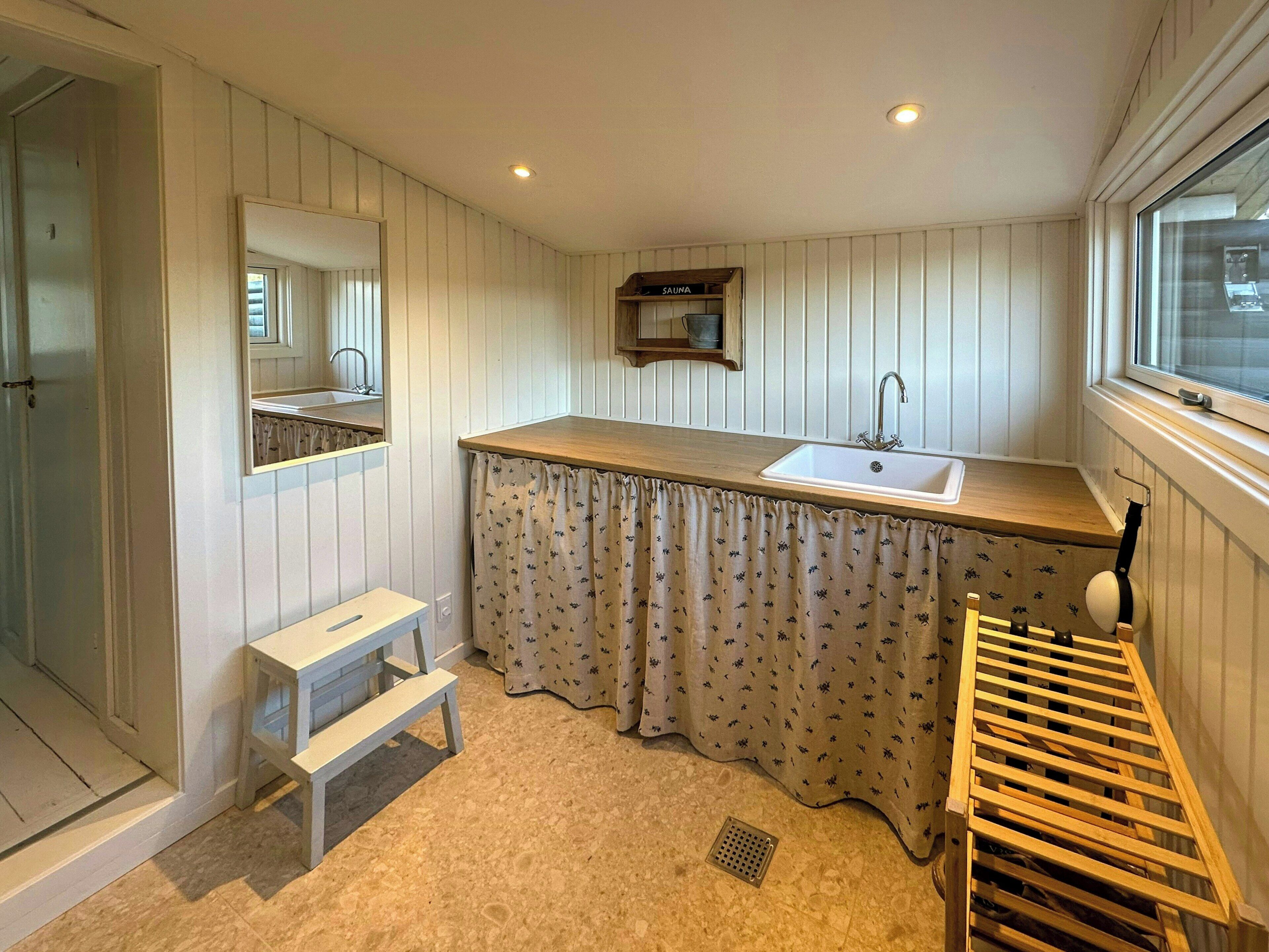 Une salle de bain avec un meuble-lavabo en bois, un évier, un miroir, une douche et une fenêtre.