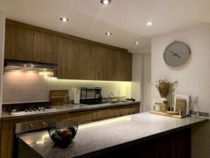 Eine moderne Küche mit Holzausstattung, einem Edelstahlherd und einer runden Uhr an der Wand.