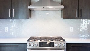 A kitchen with a stainless steel stove, dark wooden cabinets, and a hexagonal tile backsplash. - Charming 1-bedroom castle in beautiful Oakland with AC and gym (Oakland)