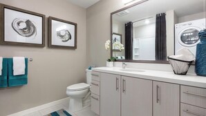 A modern bathroom with a toilet, sink, mirror, and a washing machine. - Charming 1-bedroom castle in beautiful Oakland with AC and gym (Oakland)