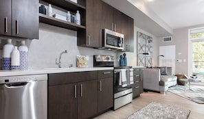 A modern kitchen with dark wood cabinets, stainless steel appliances, and a built-in microwave.