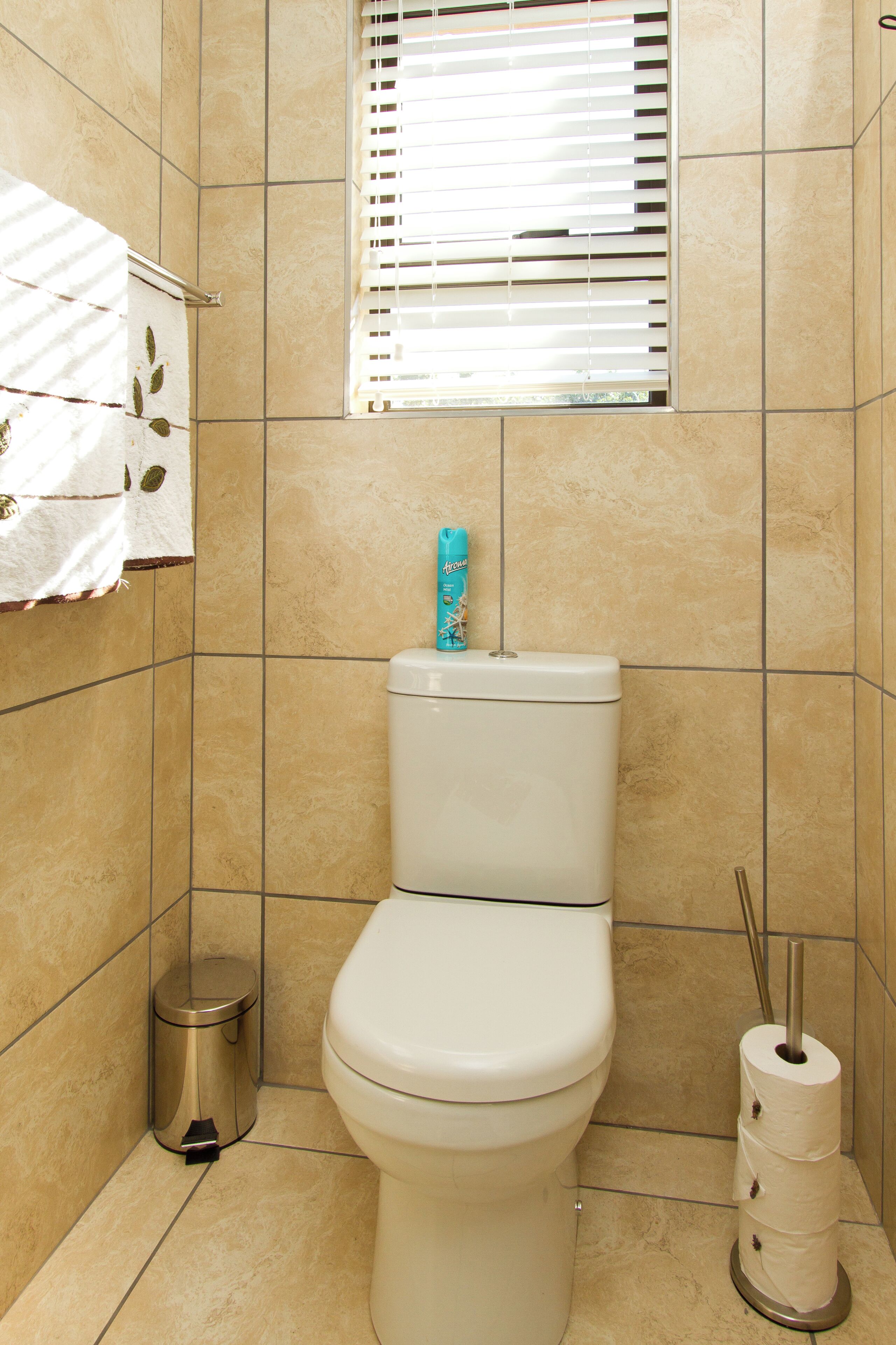 A bathroom with a toilet, a trash can, and a toilet paper holder.