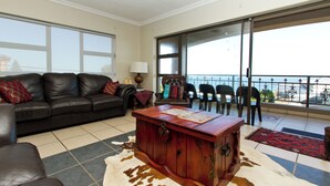 Una sala de estar con un sofá de cuero, un mueble de madera y un balcón con vistas.