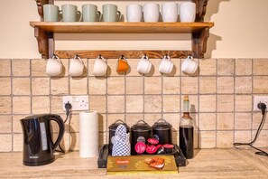 A kitchen with a coffee maker, tea kettle, and a shelf with cups and jars. - Stunning 2BR Villa with Pool (Mġarr)