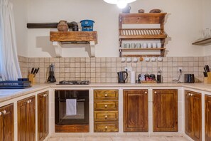 A kitchen with wooden cabinets, a tiled backsplash, and various kitchen appliances. - Stunning 2BR Villa with Pool (Mġarr)