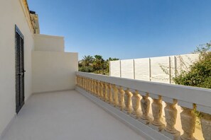 Un balcon doté d’une balustrade blanche, d’un mur blanc et d’une fenêtre avec des volets.