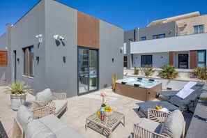 Eine moderne Terrassengrundstück mit Whirlpool, Liegestühlen und Topfpflanzen.