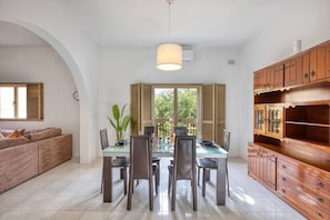 Un espace repas comprenant une table, des chaises et un luminaire suspendu.