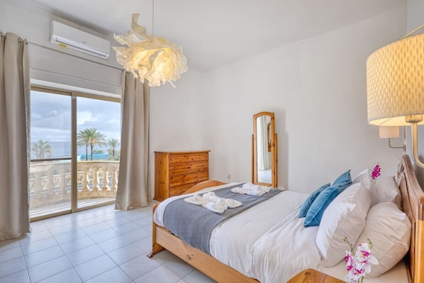Une chambre d’hôtel comprenant un lit, une commode en bois, un miroir, un balcon avec vue et un appareil de climatisation.