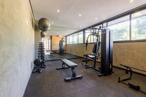 A gym with weight machines, a bench, and a mirror. - Charlie Murat Vila Madalena (São Paulo)