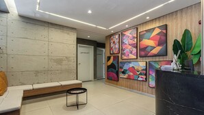 A modern lobby with a reception desk, seating area, and abstract wall art. - Charlie Murat Vila Madalena (São Paulo)