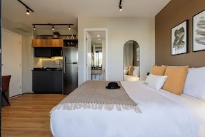 Una habitación de hotel moderna con una cama grande, un área de cocina y una mesa de comedor.