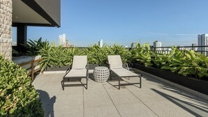 A rooftop terrace with two lounge chairs, a round table, and potted plants. - Charlie Murat Vila Madalena (São Paulo)