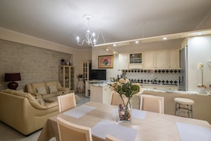 A modern living room with a sofa, dining table, and a kitchen area with cabinets and a countertop.