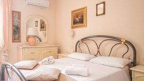 Une chambre à coucher comprenant un lit, une table de chevet, une lampe, une commode, un miroir et un appareil de climatisation.