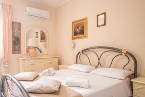 Une chambre à coucher comprenant un lit, une table de chevet, une lampe, une commode, un miroir et un appareil de climatisation.
