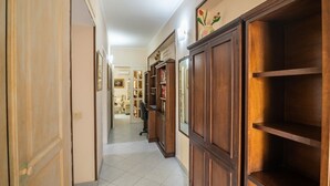 Un couloir avec des étagères en bois, une porte et un sol carrelé.
