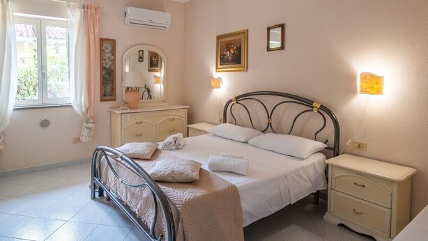 Une chambre à coucher comprenant un lit, des tables de chevet, une commode, un miroir et un appareil de climatisation.
