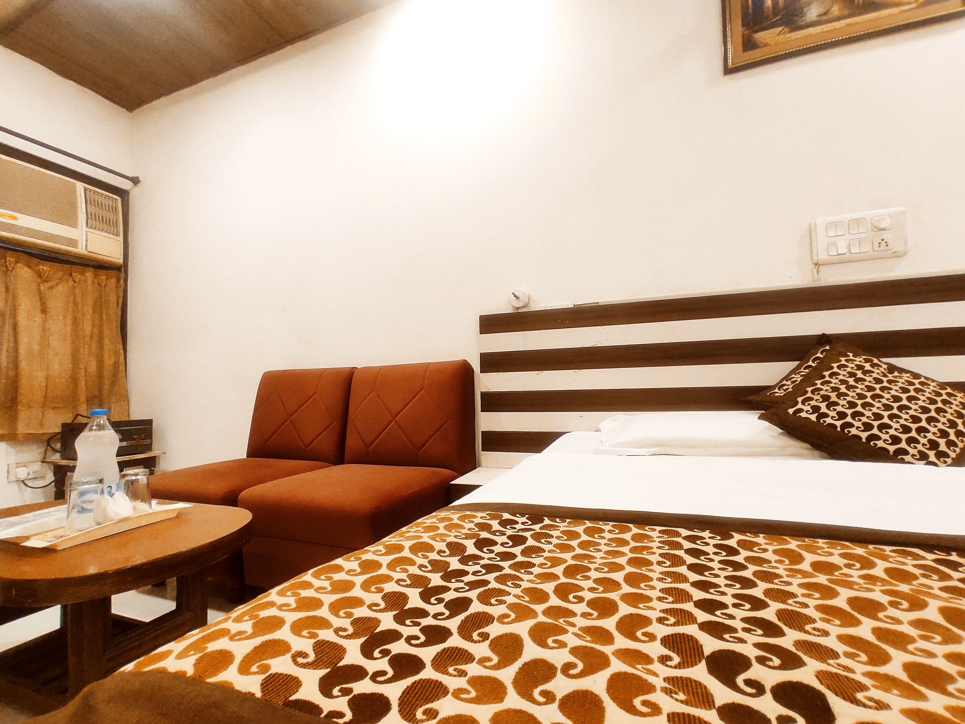 Una habitación de hotel con cama, sofá, una mesita y un radio fijado a la pared.