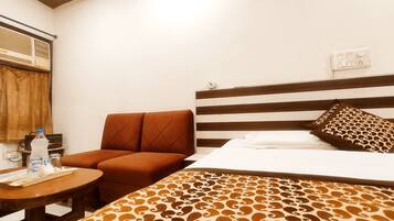 Una habitación de hotel con cama, sofá, una mesita y un radio fijado a la pared.