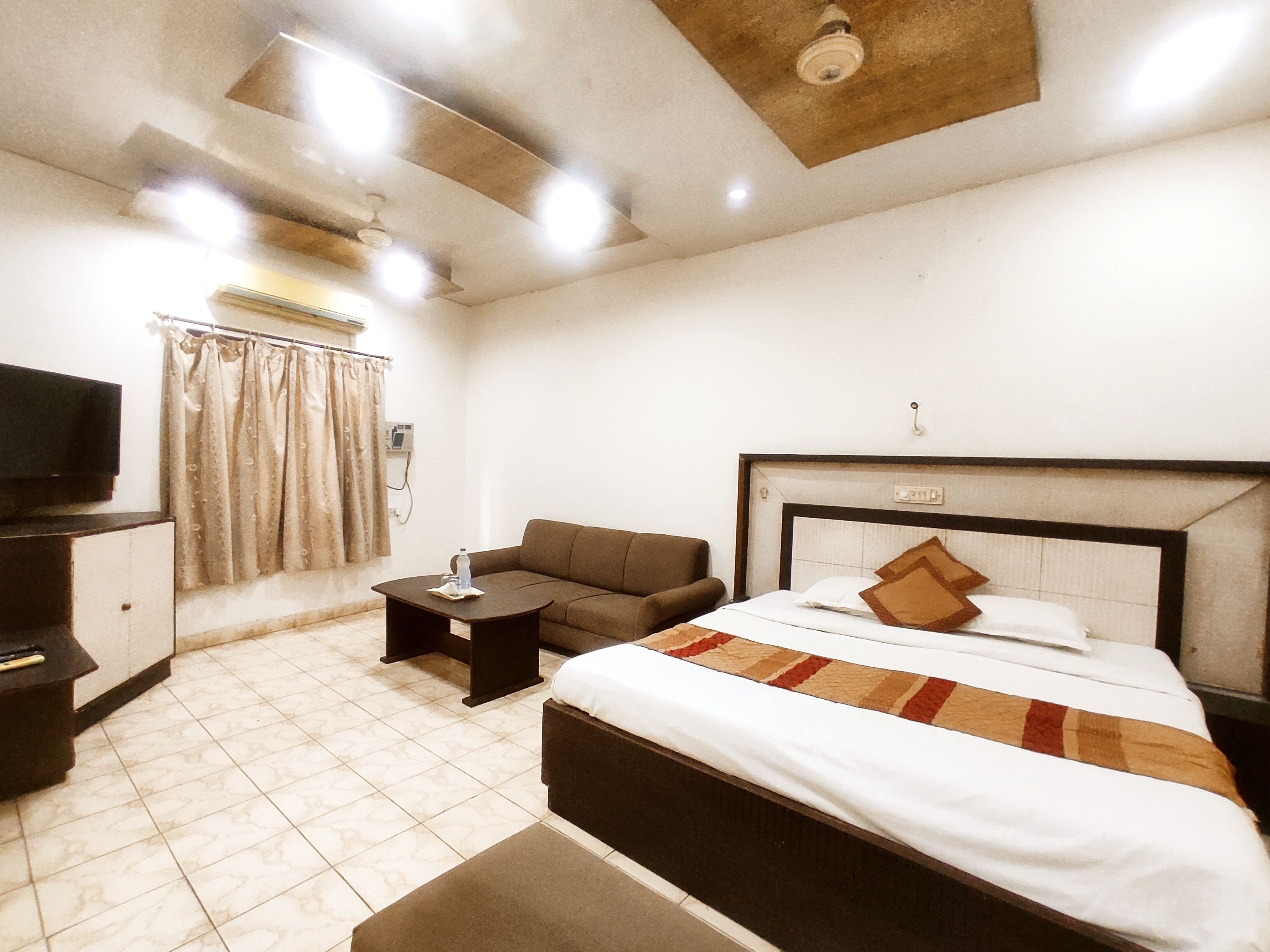 Una habitación de hotel con cama, sofá, televisión y escritorio.