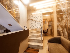 A staircase with a patterned wall, a cushioned bench, and a framed certificate on the wall.