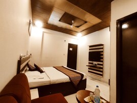 Una habitación de hotel con cama, escritorio, silla, televisor y puerta.