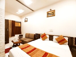 Una habitación de hotel con cama, sofá, una mesita, espejo y un cuadro en la pared.
