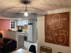 Eine moderne Küche mit weißen Schränken, einem Essbereich mit Tisch und Stühlen sowie einem einzigartigen Wandkunstwerk.